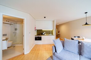 A modern apartment with a kitchenette, a shower, a sofa, and a dining area. - Superior One Bedroom for 3 Apart in Center (Oporto)