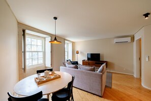 Ein modernes Wohnzimmer mit Esstisch, Sofa und Fernseher.