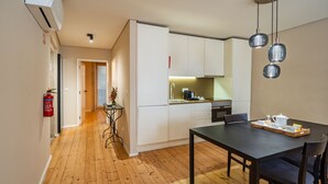 A modern kitchen with white cabinets, a dining table with chairs, and pendant lighting. - Quite One-Bedroom Apart for 3 in Center (Oporto)