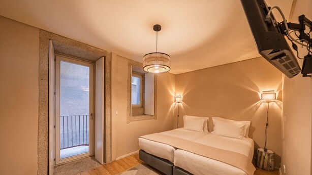 A bedroom with a bed, a door leading to a balcony, a ceiling light, and a wall-mounted TV. - Quite One-Bedroom Apart for 3 in Center (Oporto)