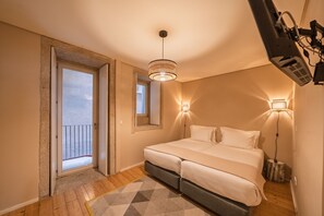 A bedroom with a bed, a door leading to a balcony, a ceiling light, and a wall-mounted TV.