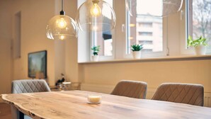 A dining area with a wooden table, four chairs, and pendant lights. - Casita Loft with 80 sqm (air-conditioned), with good transport connections (Ludwigshafen am Rhein)