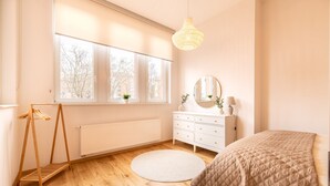 A bedroom with a bed, a dresser, a mirror, a hanging light fixture, a radiator, and a window with a view of trees. - Casita Loft with 80 sqm (air-conditioned), with good transport connections (Ludwigshafen am Rhein)
