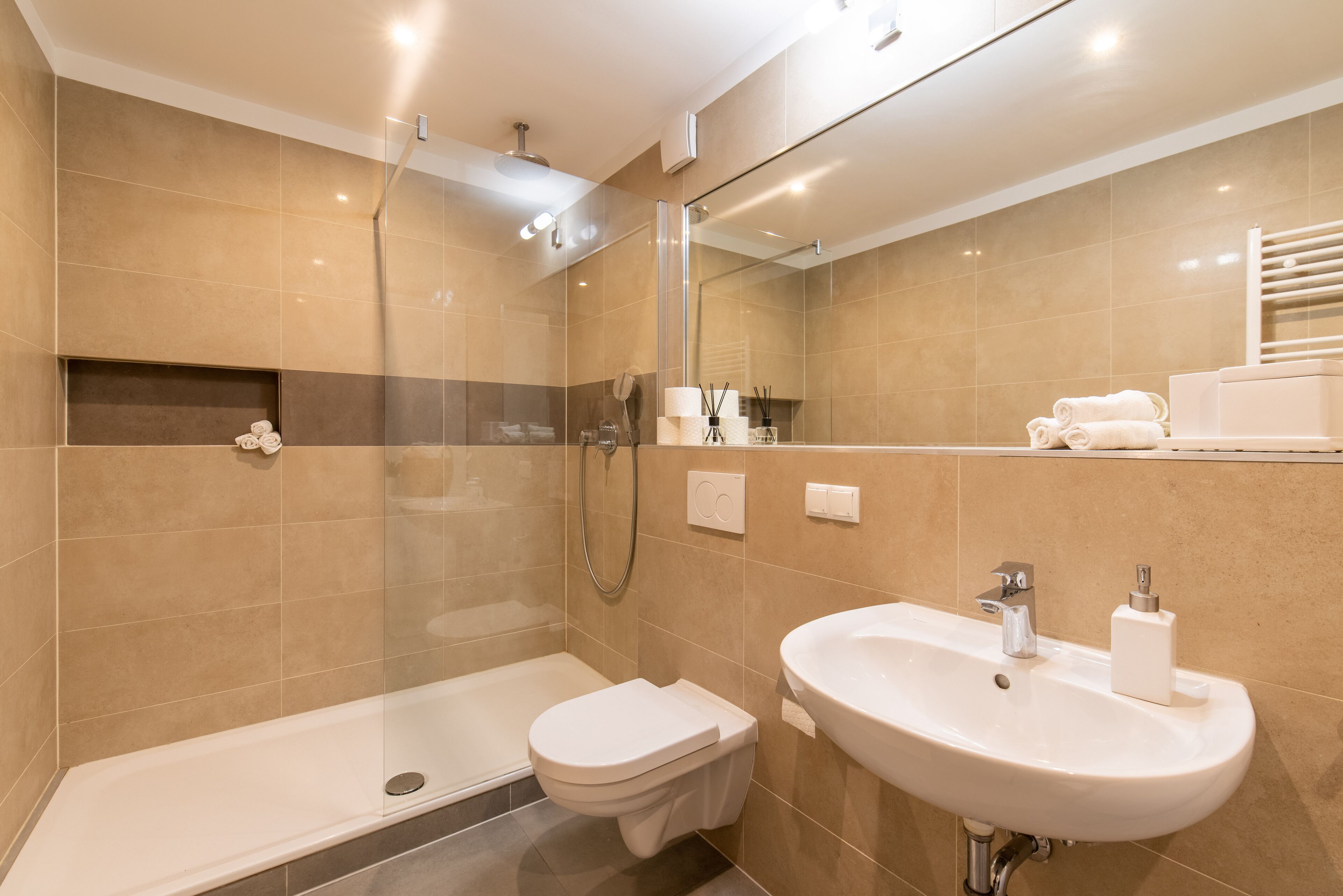 Een moderne badkamer met een douchecabine van glas, een wit wastafelmeubel en een toilet.
