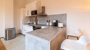 A modern kitchen with white cabinets, a stainless steel microwave, a coffee maker, and a trash can. - Casita Loft with 80 sqm (air-conditioned), with good transport connections (Ludwigshafen am Rhein)