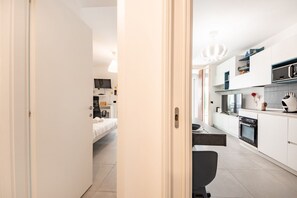 A modern kitchen with white cabinets, a microwave, and a built-in oven. - GuestHost - Bright, spacious and renovated apartment of 50mq with small private garden located on the first floor of a building with lift that can accommodate up to 4 people! The house is equipped with the main comforts and is perfect for tourist or busi (Milano)