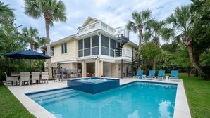 A two-story house with a swimming pool, outdoor furniture, and palm trees. - Home on Beach Boardwalk! Private Pool! Amenity Cards! (Seabrook Island)