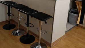 Een keuken met een bar, twee magnetrons, een spoelbak en een prullenbak.