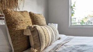 A bed with two textured pillows and a striped pillow with tassels.