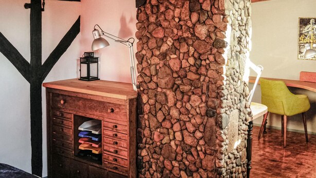 Un interno rustico con una scrivania in legno, un muro in pietra e una sedia gialla.