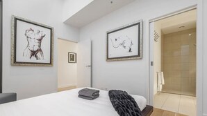 A modern bedroom with a large bed, a black throw blanket, and two framed artworks on the walls. - "The Sophia" Milan meets New York in Melbourne (Cremorne)
