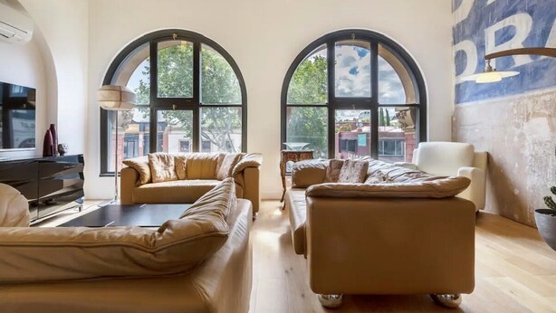A spacious living room with two sofas and a coffee table, large arched windows, and a city view. - "The Sophia" Milan meets New York in Melbourne (Cremorne)