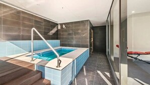 A modern bathroom with a glass-enclosed shower, a wooden floor, and a tiled floor leading to a pool area. - "The Sophia" Milan meets New York in Melbourne (Cremorne)