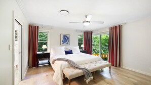 Un dormitori amb llit, ventilador de sostre i finestra amb cortines.