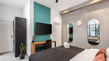 Habitación de hotel moderna con cama, escritorio, televisor y una planta en maceta.