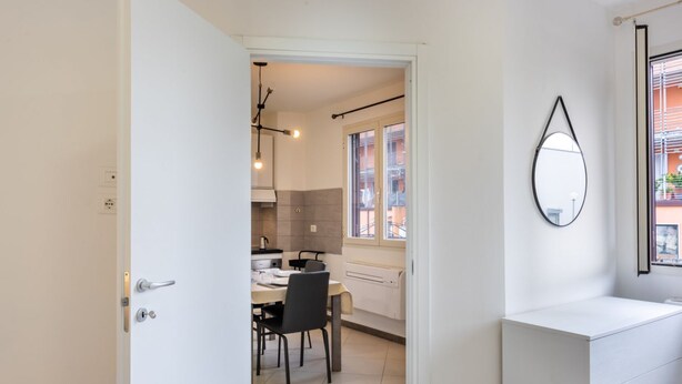 Una cocina moderna con comedor, una pared blanca con espejo y vistas al exterior.