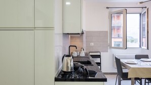 Una cocina moderna con estufa a gas, hervidor y comedor con mesa y sillas.