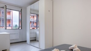 Una habitación de hotel moderna con una cama, un espejo, un ventanal y vista a un edificio.