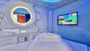 A modern room with a bed, a control panel, a digital screen, and a circular light fixture. - Atypicap Capsule Hostel (Puerto de la Cruz)