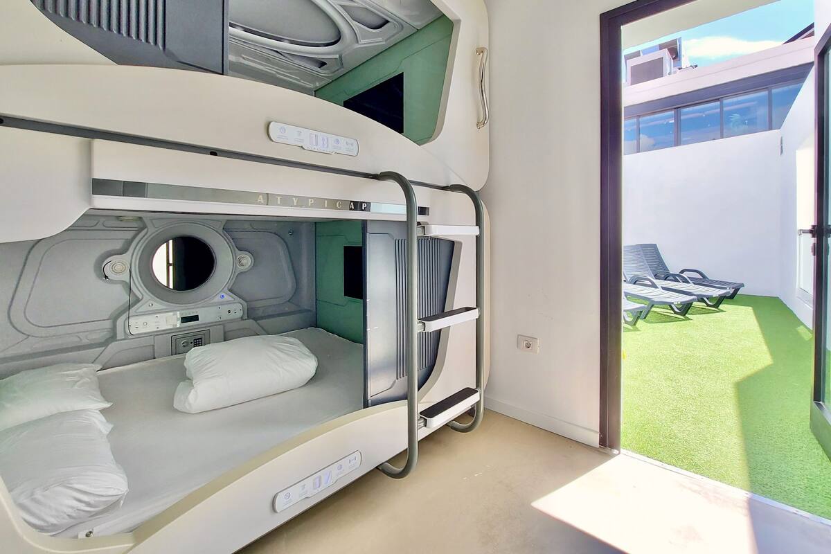 A hotel room with bunk beds, a built-in washer, and a view of a green outdoor area.