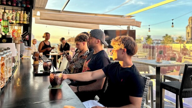 A bar with a counter, bottles, and a menu. - Atypicap Capsule Hostel (Puerto de la Cruz)