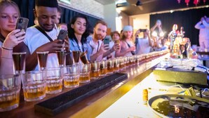 Un bar con una barra alargada, vasos de cerveza y un cantinero.