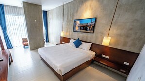Una habitación de hotel moderna con una cama grande, un televisor de pantalla plana montado en la pared y vistas a la ciudad a través de la ventana.