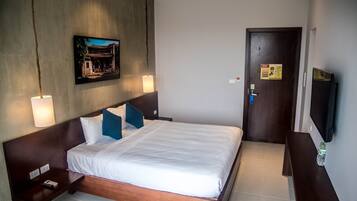 A hotel room with a large bed, a nightstand, a wall-mounted TV, and a painting above the bed.