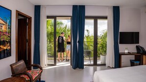 Una habitación de hotel con balcón, cama, escritorio y silla.