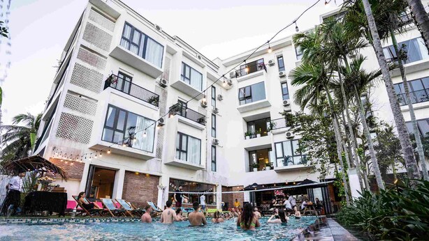 Un hotel moderno con zona de piscina, asientos al aire libre y restaurante.