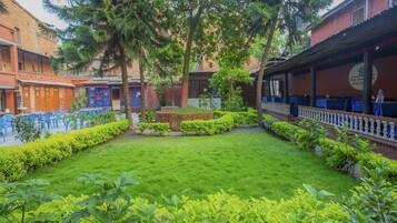A courtyard with a well-maintained lawn, surrounded by buildings with brick facades and blue chairs.