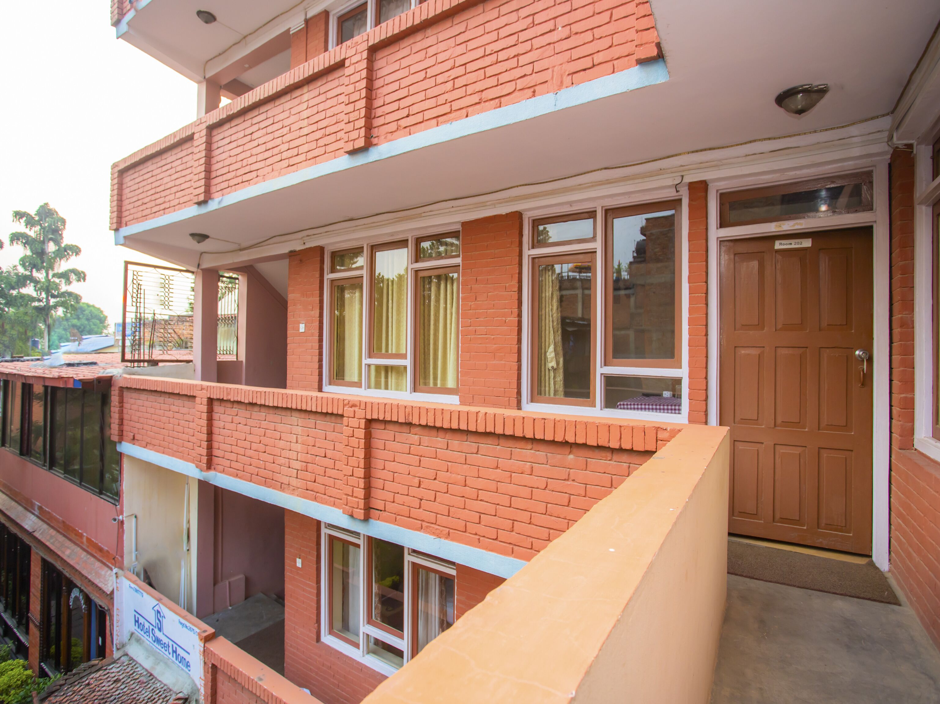 A multi-story hotel with a red brick facade, multiple windows, and a visible entrance door.