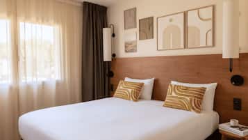 Una camera d'albergo con un letto grande, un comodino, una lampada e decorazioni alle pareti.