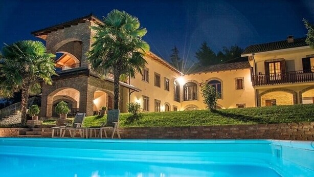 Una casa grande de varios pisos con una piscina al frente.