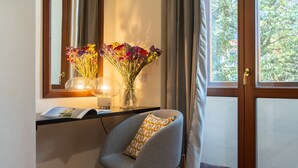 A room with a desk, a chair, a vase with flowers, and a window with curtains. - SPIRIT OF FLORENCE Boutique Rooms (Florence)