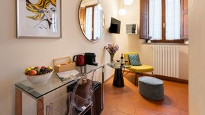 A modern living room with a glass coffee table, a sofa, a small dining table, and a large mirror. - SPIRIT OF FLORENCE Boutique Rooms (Florence)