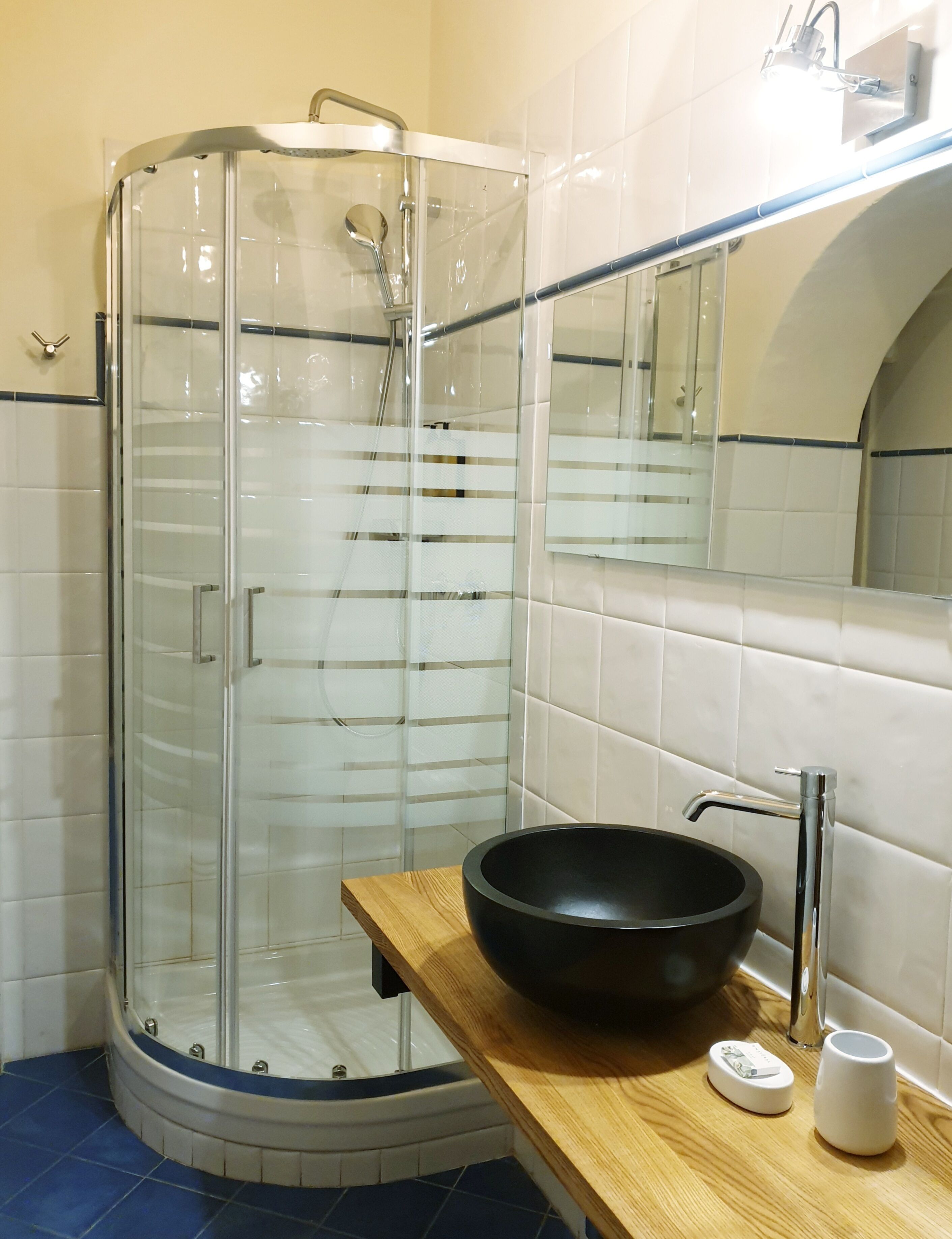 Une salle de bain moderne avec une douche à parois de verre, un lavabo noir sur pied et un meuble-lavabo en bois.