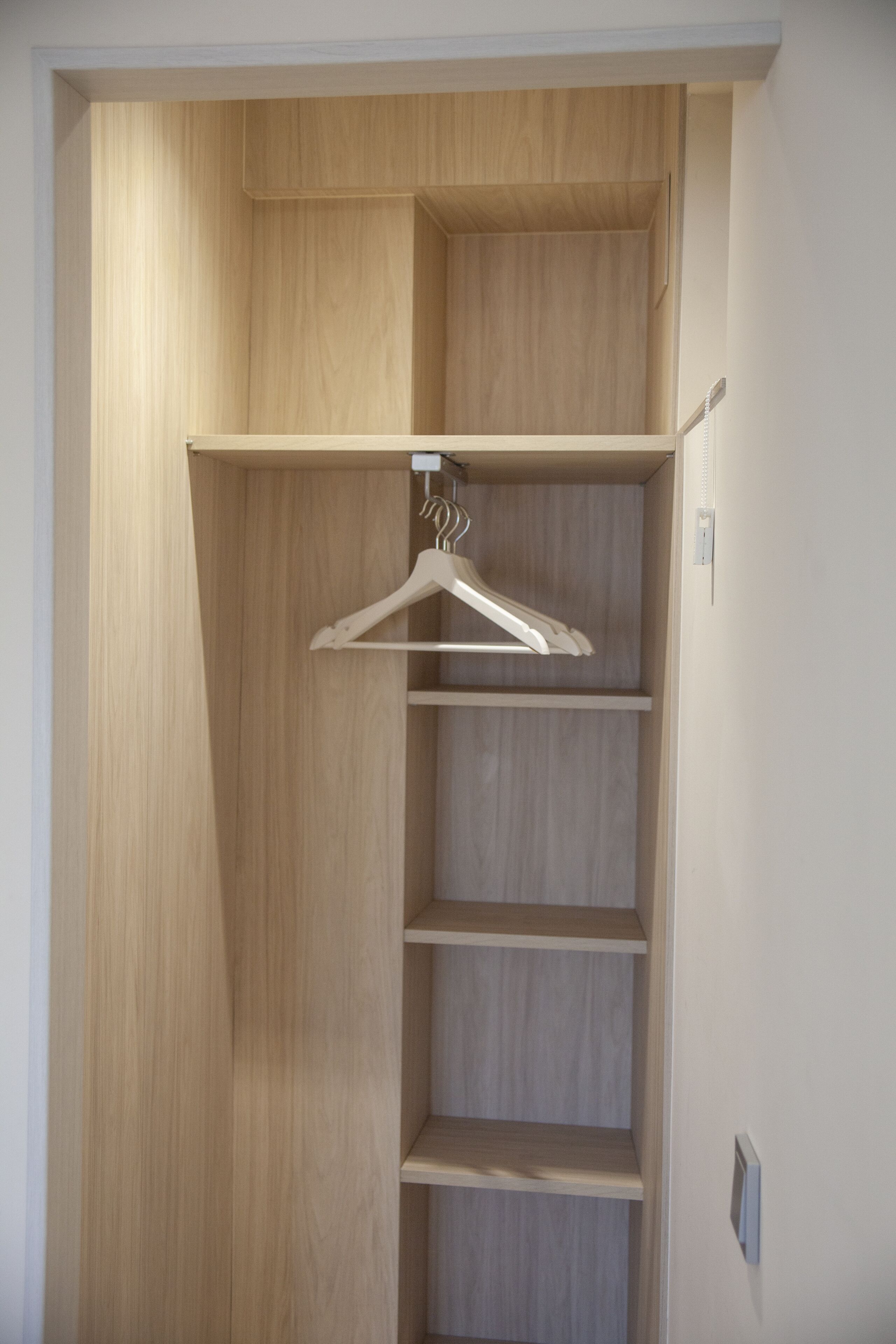 A wooden wardrobe with multiple shelves and a hanging rod.