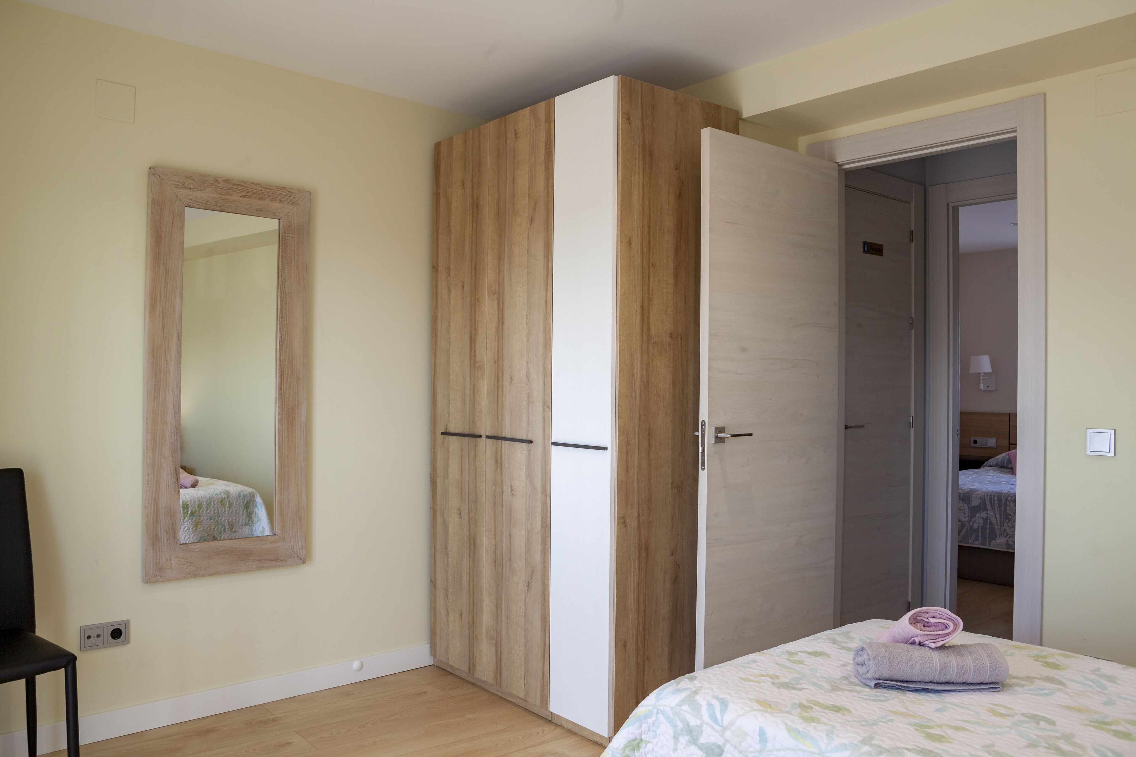 Un dormitorio con cama, armario y espejo.
