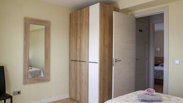 Un dormitorio con cama, armario y espejo.