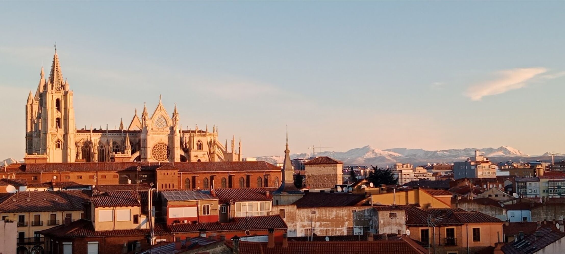 Una catedral històrica d'arquitectura detallada, envoltada d'edificis tradicionals i un paisatge de muntanyes.