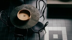 A round table with a wooden bowl on top, surrounded by four chairs. - WELTWIEN Apartments (Vienna)
