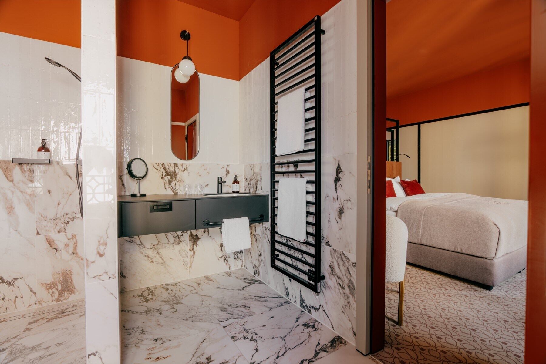 A modern bathroom with a marble floor, a black towel rack, a mirror, and a shower.