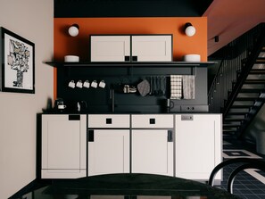 A modern kitchen with white cabinets, a black countertop, and a staircase in the background. - WELTWIEN Apartments (Vienna)