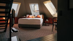 A bedroom with a bed, two nightstands, a chair, and a skylight. - WELTWIEN Apartments (Vienna)