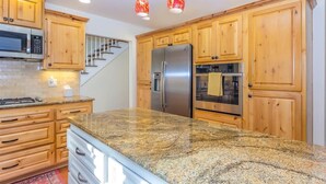 A kitchen with wooden cabinets, granite countertops, stainless steel appliances, and a staircase. - Spacious Mt. Bachelor Retreat w/ Hot Tub + Pets OK (Bend)