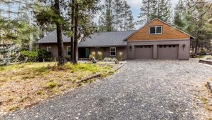 A two-story house with a gravel driveway, surrounded by trees. - Spacious Mt. Bachelor Retreat w/ Hot Tub + Pets OK (Bend)
