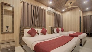 Quarto de hotel com duas camas, cabeceiras de madeira e ventilador de teto.
