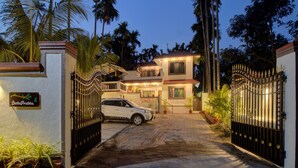 Entrada com portão para uma casa de dois andares, com um carro branco estacionado na frente.