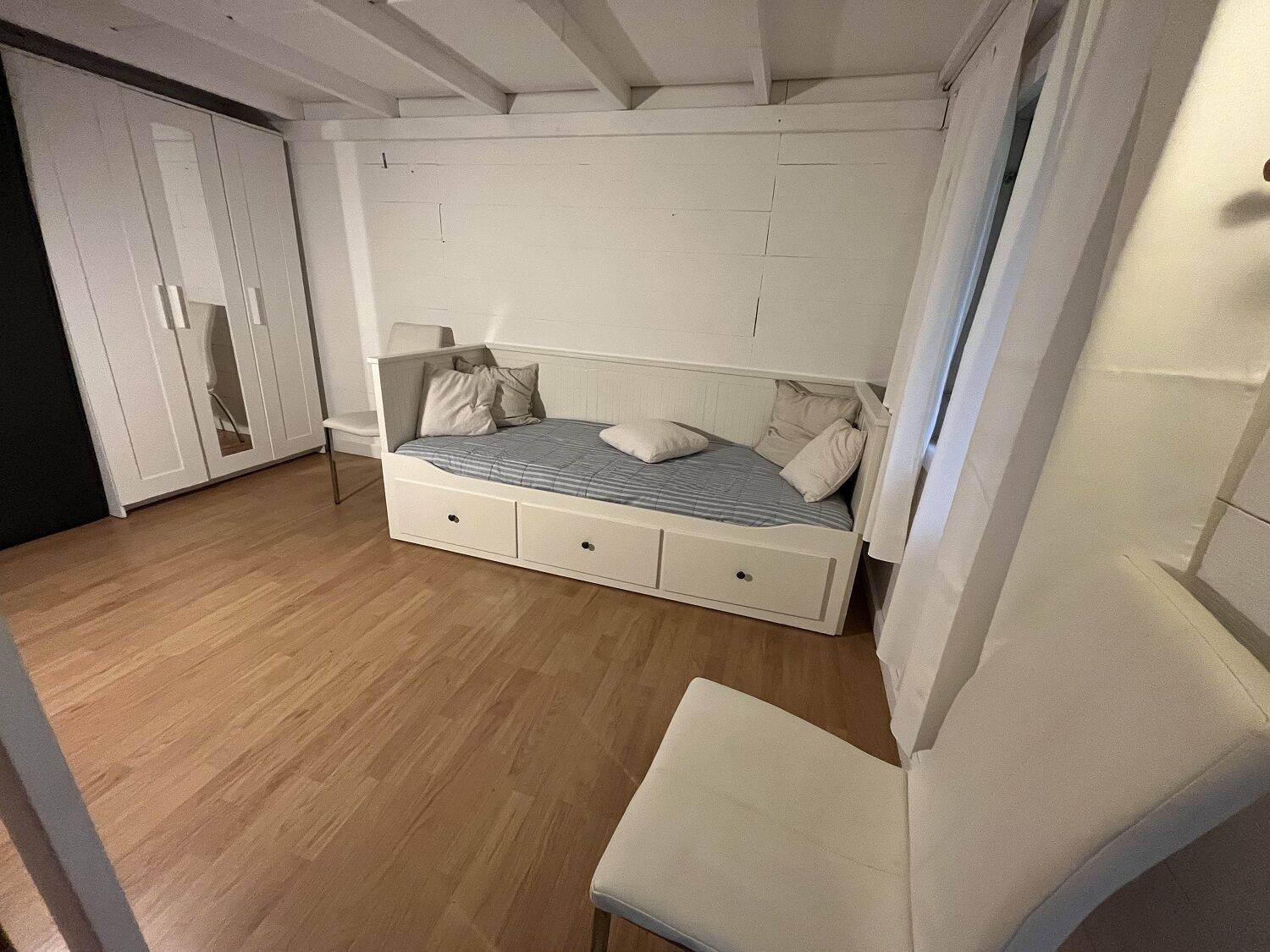 A bedroom with a bed, a chair, and a wardrobe.